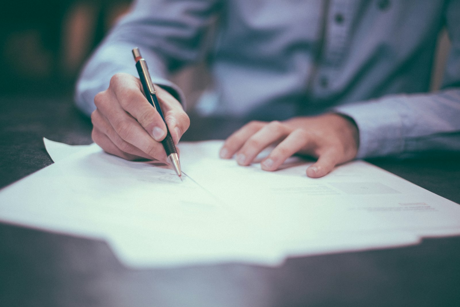 Person writing on a document at a desk
